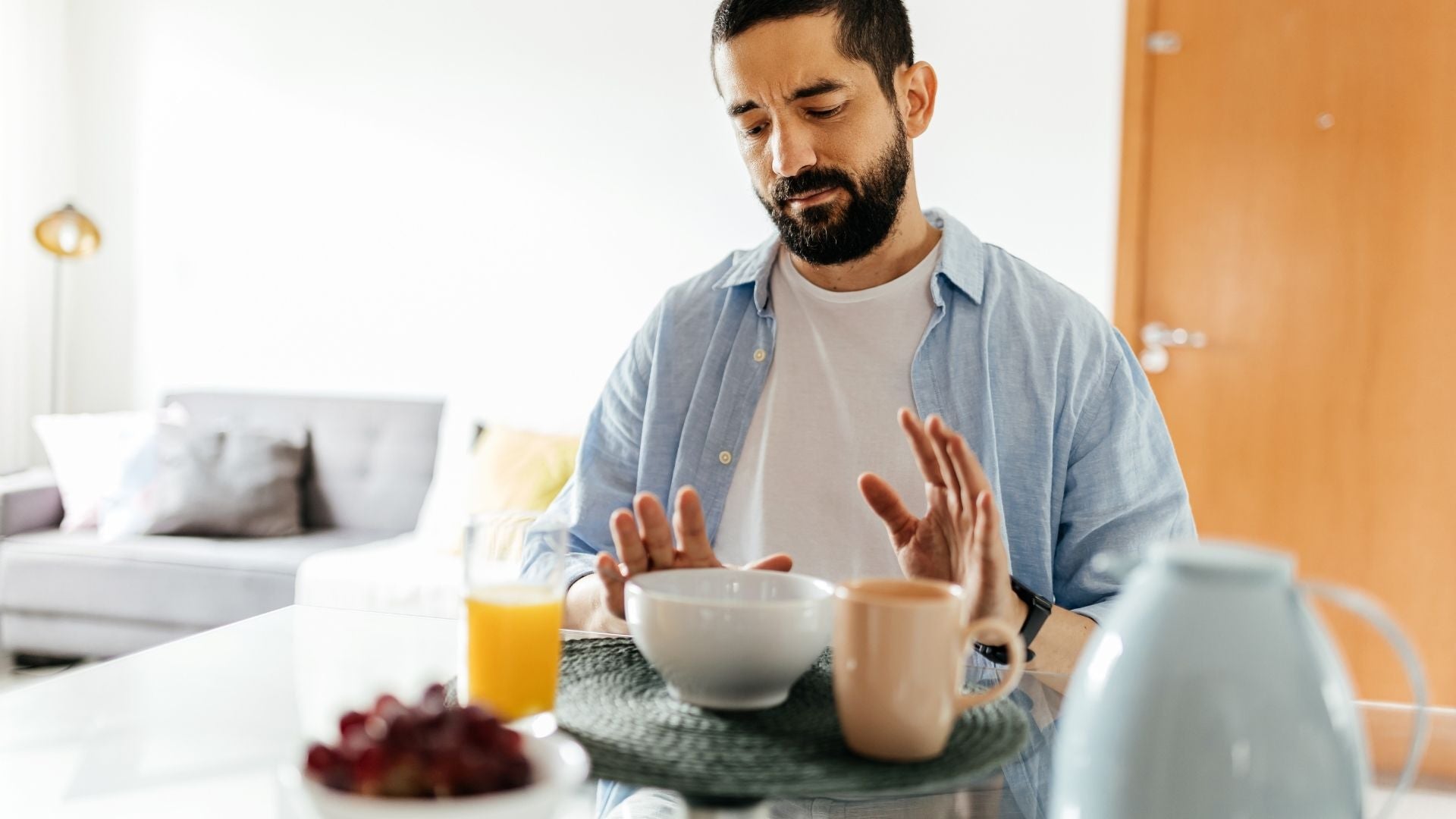 Hombre sentado en una mesa con un tazón de cereal y una taza de café, reflejando ansiedad digestiva.