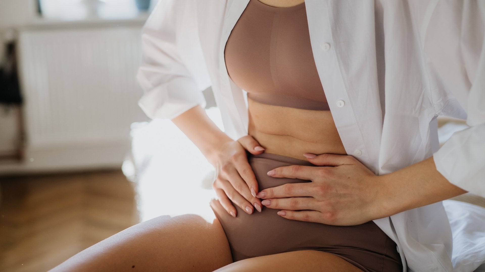 Mujer con expresión de dolor, sosteniendo su abdomen con una mano, indicando malestar estomacal.