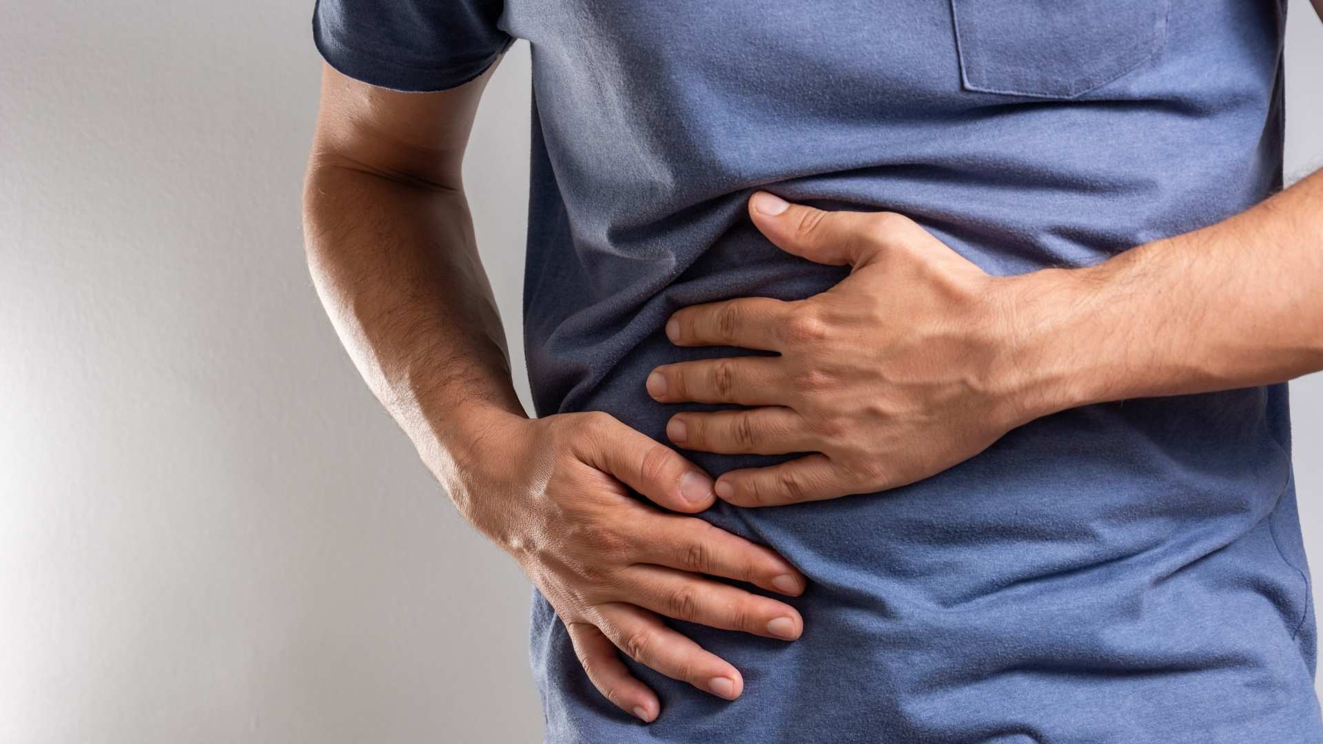 Hombre con las manos en el estómago, reflexionando sobre la necesidad de un "reset" digestivo en su cuerpo.