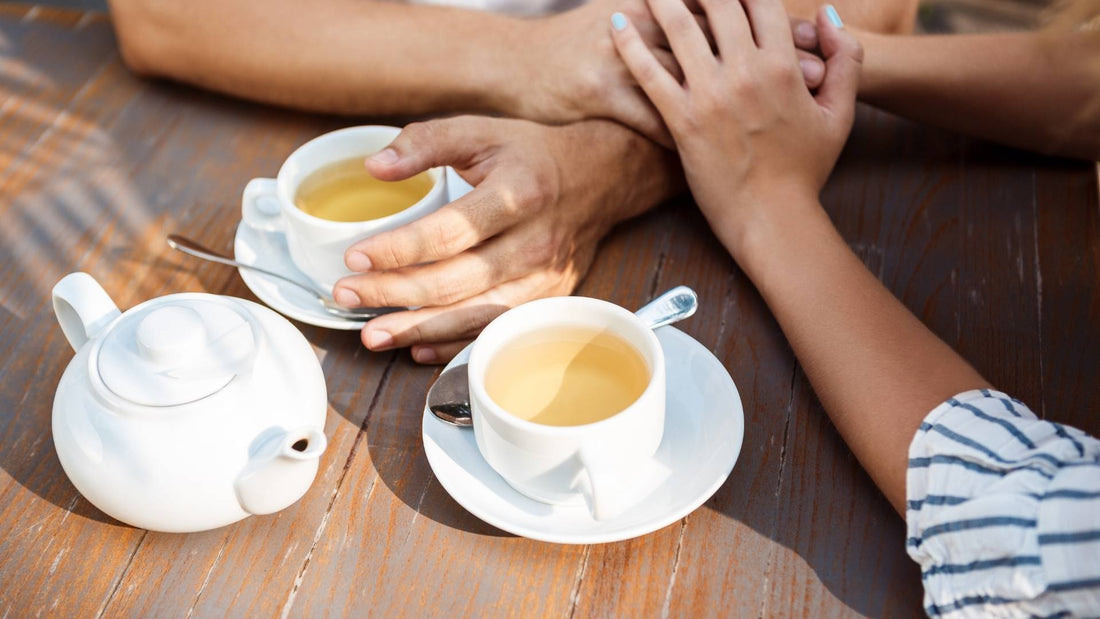 Pareja tomando té y tomados de la mano, simbolizando bienestar y conexión en el mes de #GenTeaLovers.