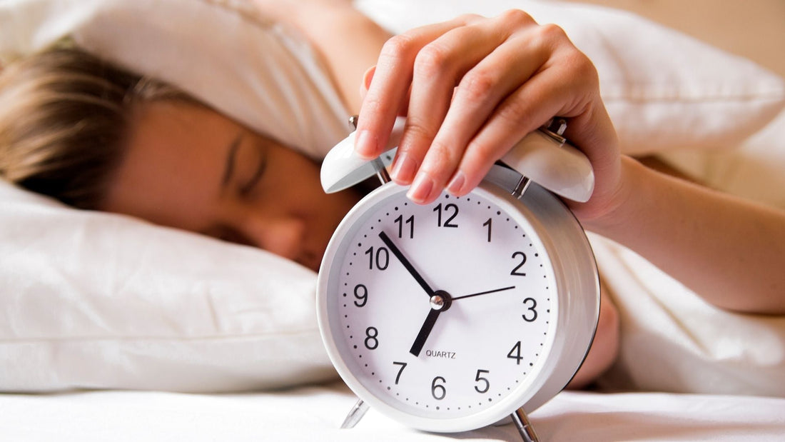 Mujer durmiendo junto a un reloj despertador.