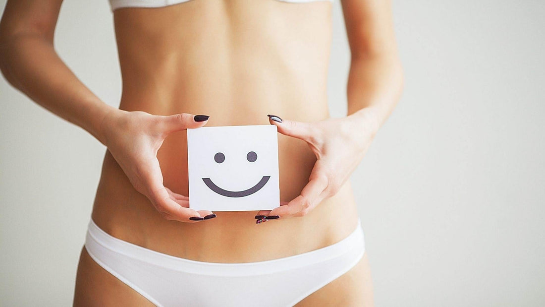 Mujer en ropa interior sosteniendo una tarjeta con una cara sonriente, simbolizando felicidad y metabolismo activo.