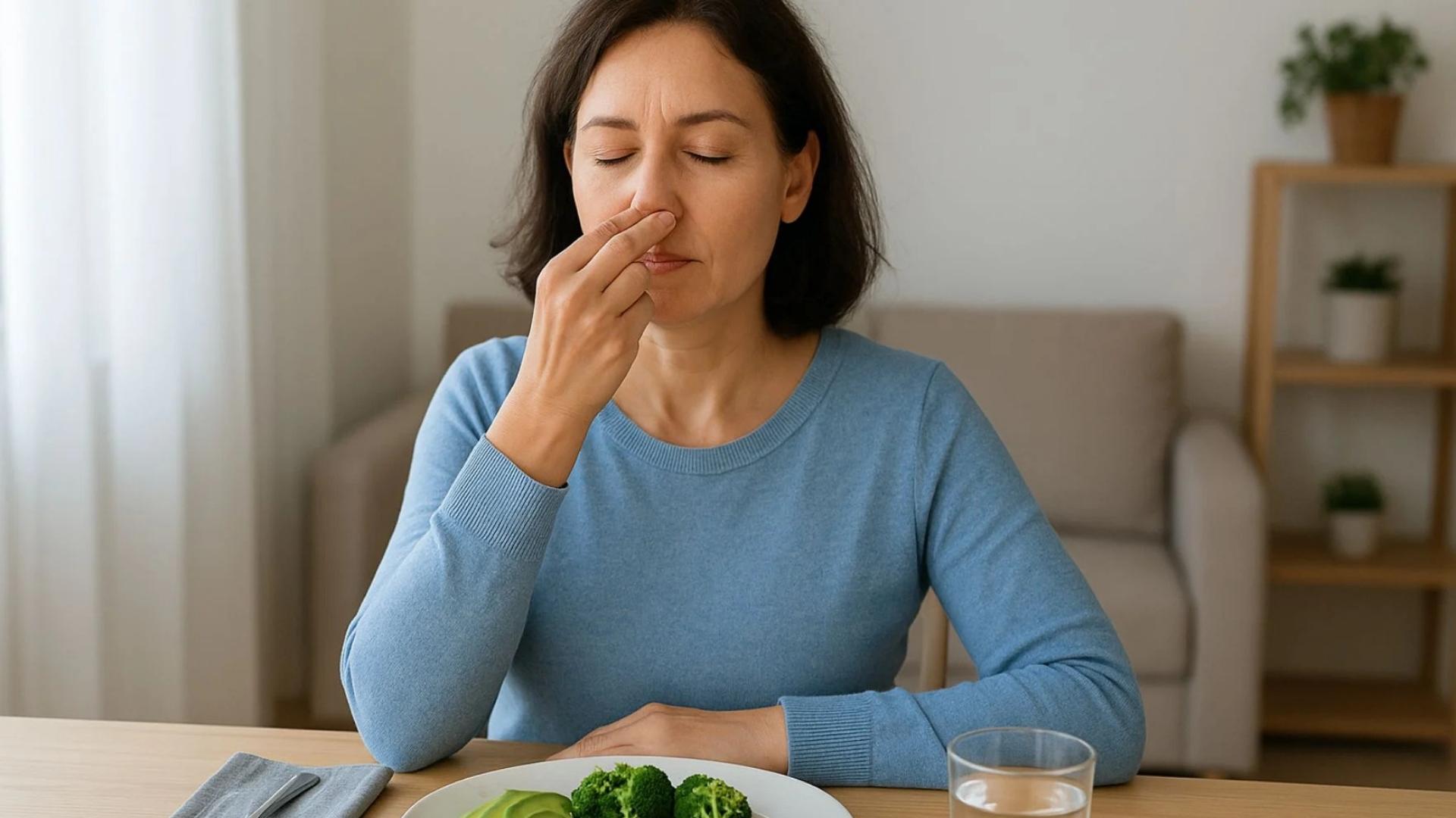 Mujer comiendo brócoli en una mesa.