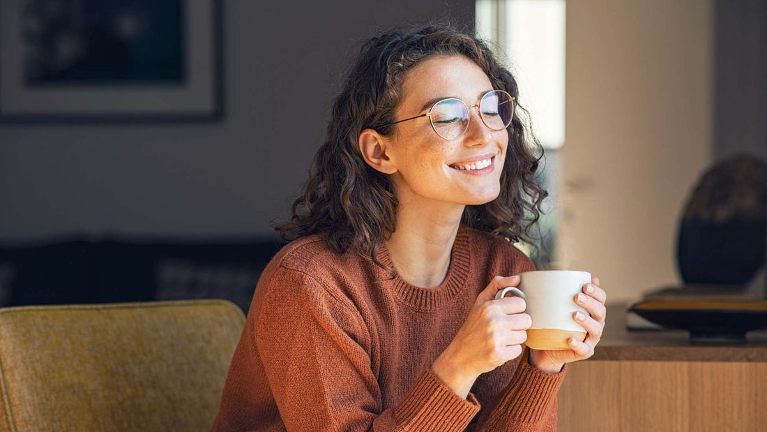 Mujer con gafas disfrutando de una taza de café en su ritual matutino.