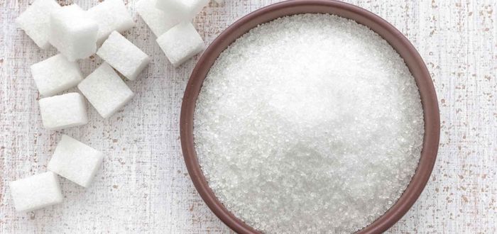 Cubos de azúcar y azúcar suelta en un tazón, mostrando diferentes formas de este edulcorante.
